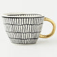 Tasse mit abstraktem geometrischem Muster und goldenem Henkel